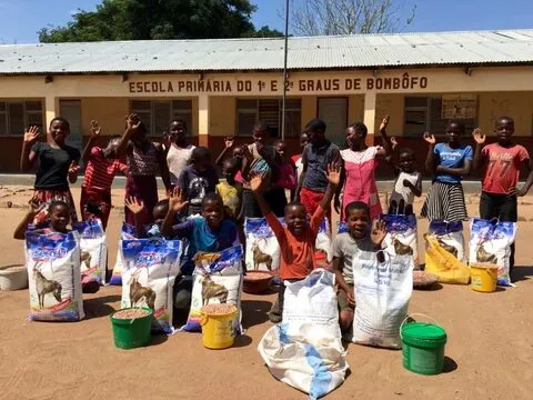 Alunos com sacos de cestas básicas à frente da escola primária de Bombôfo