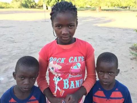Uma menina de blusa vermelha com dois rapazes mais novos