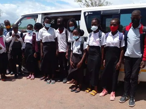Alunos do secundário de camisa branca e máscara ao lado do minibus da IMOLE