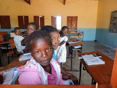 Uma menina levanta os olhos da carteira numa sala de aula