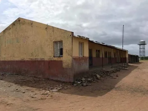 Um edifício escolar amarelo num pátio de areia