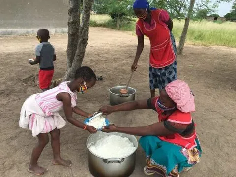 Uma menina recebe o almoço de uma panela grande